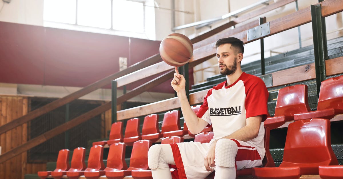 What determines whether or not you spin out when damaged? - Low angle of young male sportsman in professional uniform sitting on sports seat of basketball court and spinning ball while looking away