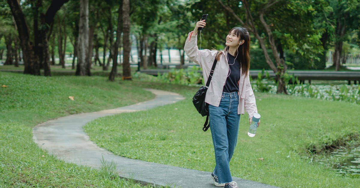 What direction to walk in to capture a targeted Pokemon? - Smiling woman taking selfie in park