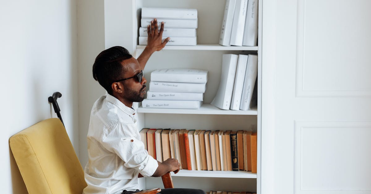 What do I get for getting Poke-Bank? - Man in White Dress Shirt Sitting on Brown Wooden Chair Reading Books