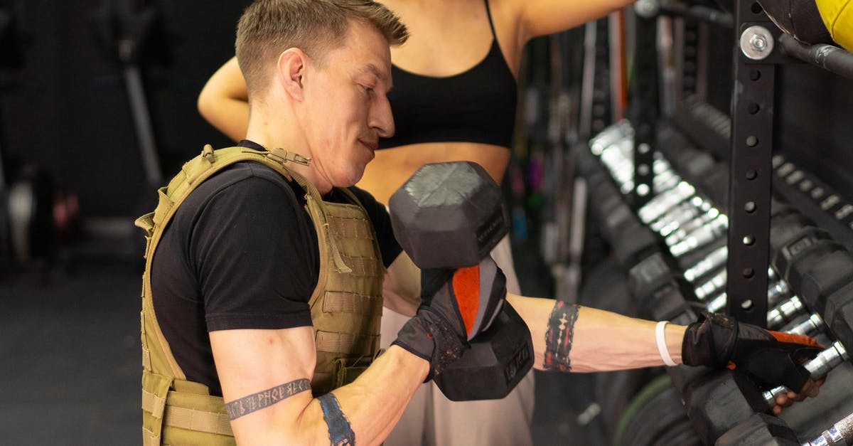 What do I get for holding gyms? - Side View of a Man in a Weighted Vest Holding a Dumbbell