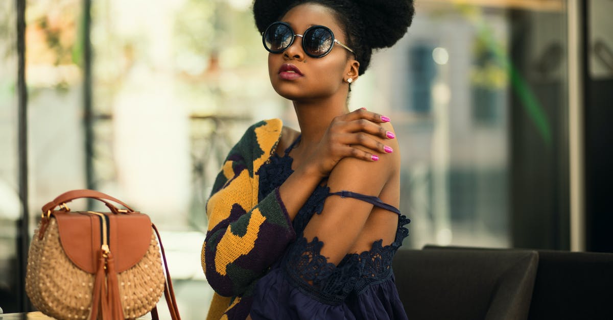 What do the model numbers on Bastion's body represent? - Shallow Focus Photography of Woman Wearing Gray and Yellow Spaghetti Strap Dress Sitting on Chair