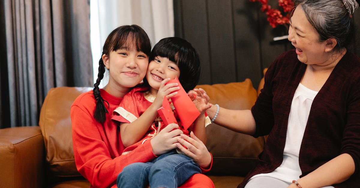What do the red paths mean in pocket planes? - Smiling ethnic female adolescent embracing sibling with red pocket against grandma on couch during New Year holiday at home