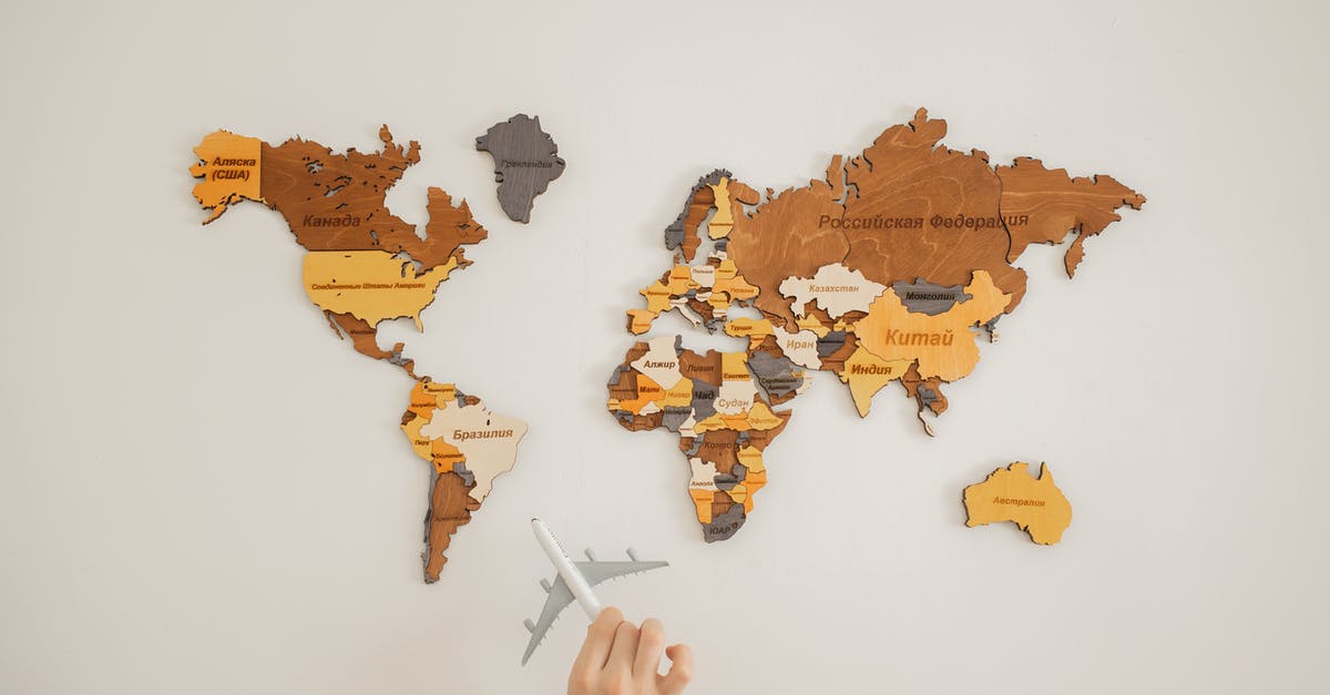 What do these strings below the map names mean? - Crop unrecognizable person with toy aircraft near multicolored decorative world map with continents attached on white background in light studio