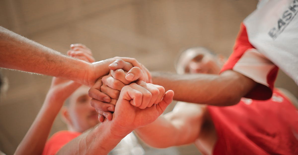 What does BM stand for in Gaming? - From below of crop multiethnic team of professional basketball players gathering and putting hands together while standing on playground before game