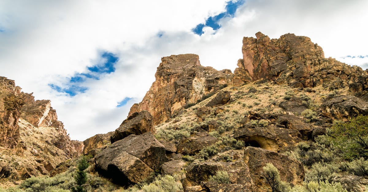 What does it mean when something charges at me from the tall grass? - From below of hill slope with rough rocky formations and small bushes under cloudy sky in daylight