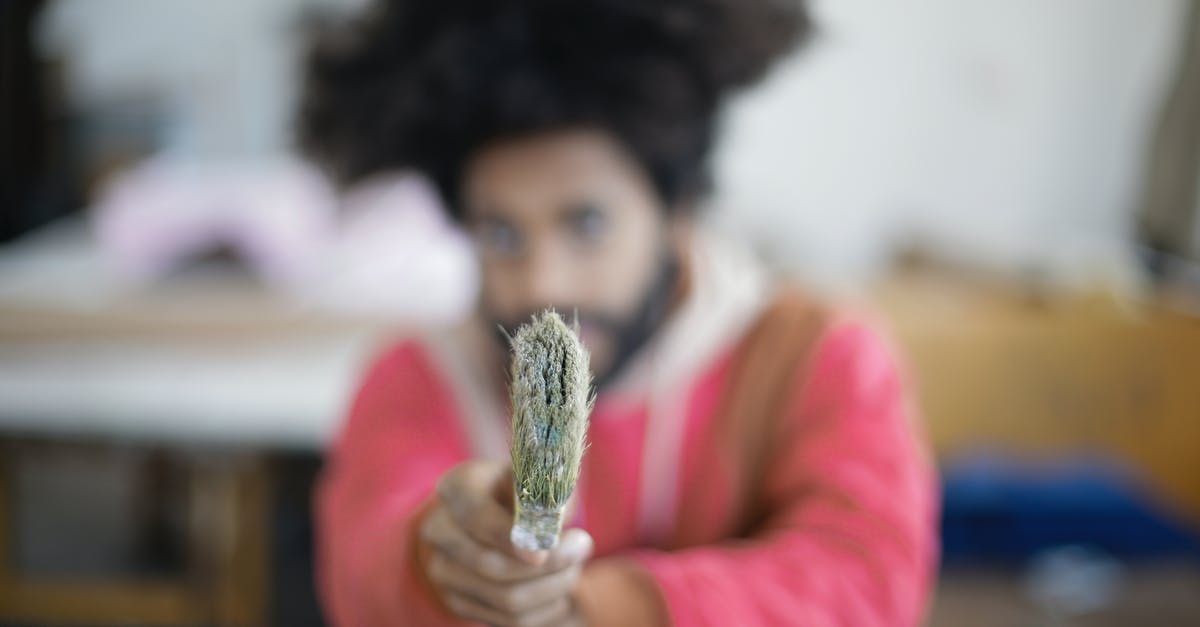 What does the arrow mean when you pick up a weapon? - Unrecognizable young bearded ethnic craftsman pointing with paintbrush at camera sitting at table in modern creative workshop