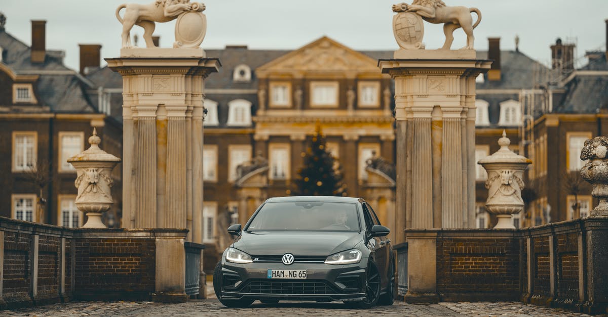 What does the black goddess statue do and what is it? - Contemporary powerful car parked in gate against historic building with stucco works and statues on cloudy day