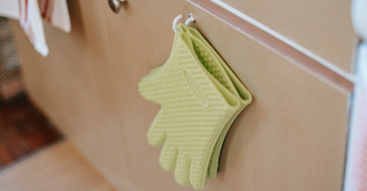 What does the door want from me? - Pair of oven gloves on cabinet door in kitchen