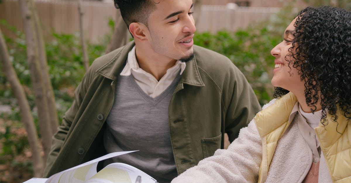 What does the full research tree look like for XCOM 2? - Smiling young Hispanic couple in warm clothes sitting at table while preparing for exams with textbook near green shrubs and trees in daylight in park while looking at each other