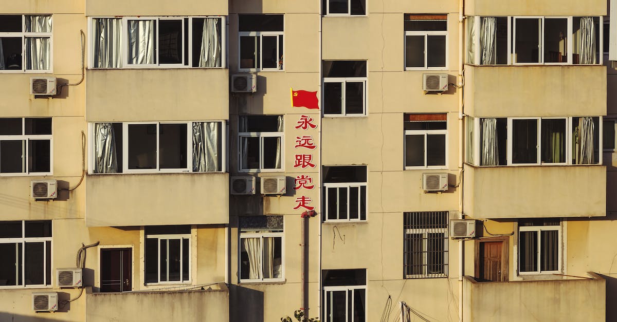 What does the gossip stone message about "crows that fly near the town walls" mean? - Facade of high building with red Chinese inscription in residential area in light of sun
