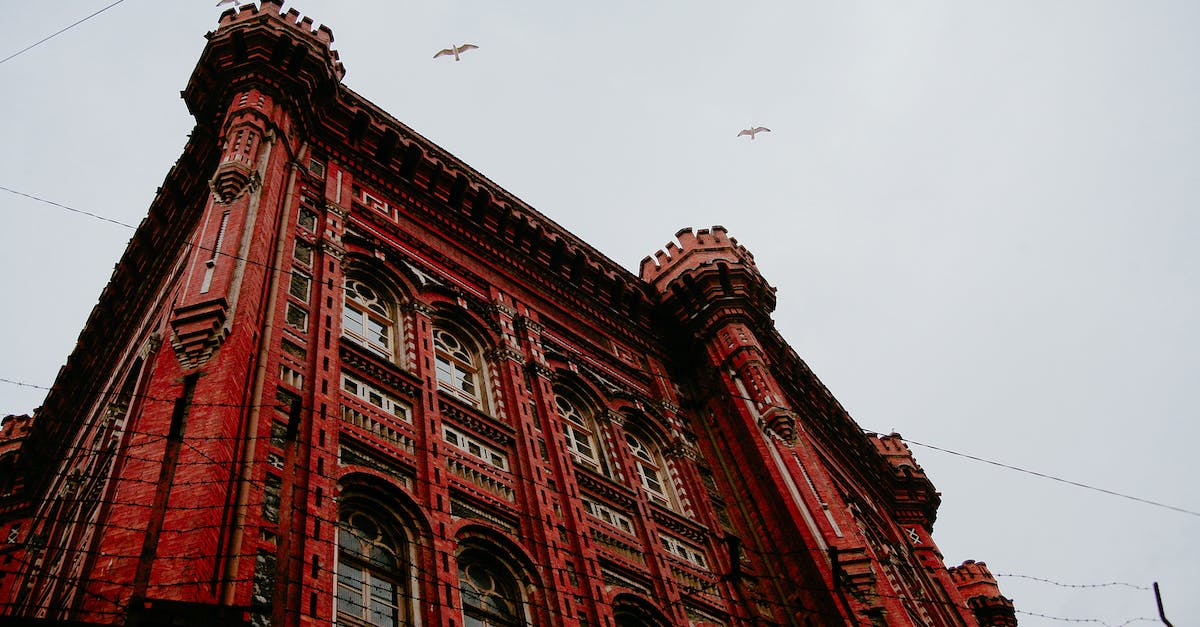 What does the gossip stone message about "crows that fly near the town walls" mean? - From below of aged masonry lyceum exterior with arched windows and ornamental walls under soaring birds in Istanbul