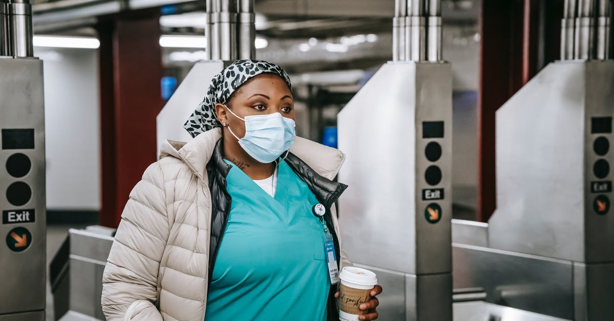 What does the season pass include? - Black nurse in outerwear and mask passing turnstile in underground What does the season pass include? - Black nurse in outerwear and mask passing turnstile in underground