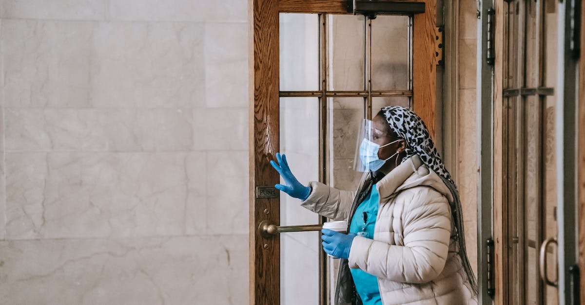 What does the Shield over a city mean? - Black nurse in respirator and gloves leaving modern building