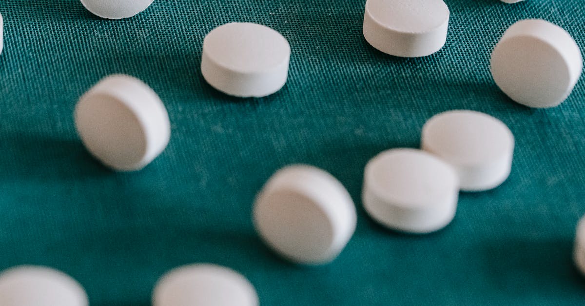 What does the size of the multicoloured circle mean? - Closeup of similar round white pills spilled on green tissue in random order