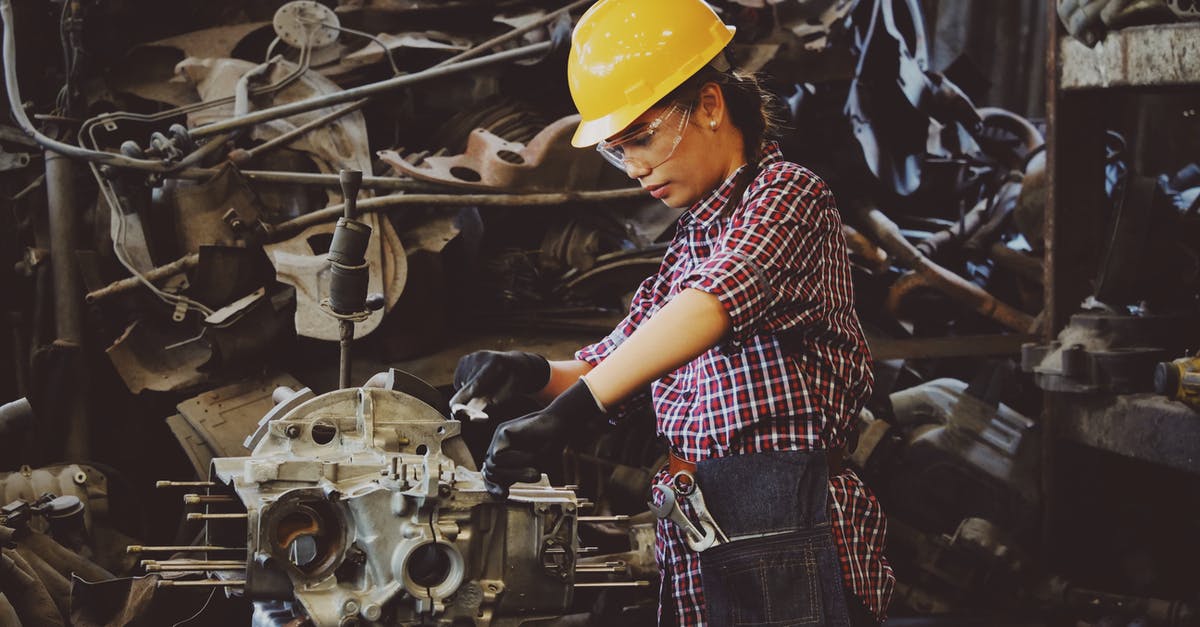 What does the SOS mechanic do? - Woman Wears Yellow Hard Hat Holding Vehicle Part What does the SOS mechanic do? - Woman Wears Yellow Hard Hat Holding Vehicle Part