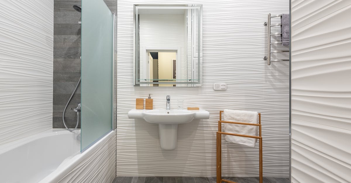 What does the T stand for in Tap Titans? - Contemporary bathroom interior with bathtub and washstand with toiletry products under mirror in light house