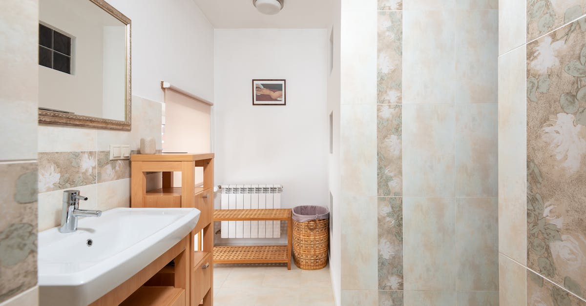 What does the T stand for in Tap Titans? - Cupboard with sink and faucet placed near wooden stand and mirror hanging on wall against wall with abstract design in bathroom