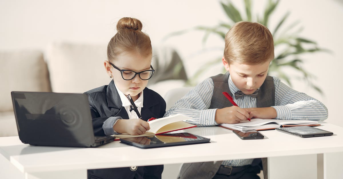 What exactly happens during "Puff-Puff"? - Cute business children in uniform using laptop and writing information in planners while making up startup strategy in modern workspace