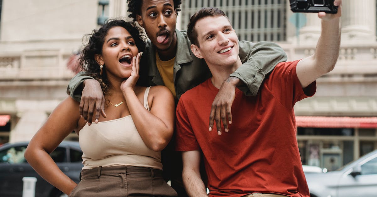 what exactly makes the car stealthy? - Positive young multiethnic friends in casual clothes taking selfie on phone while making funny faces in city street