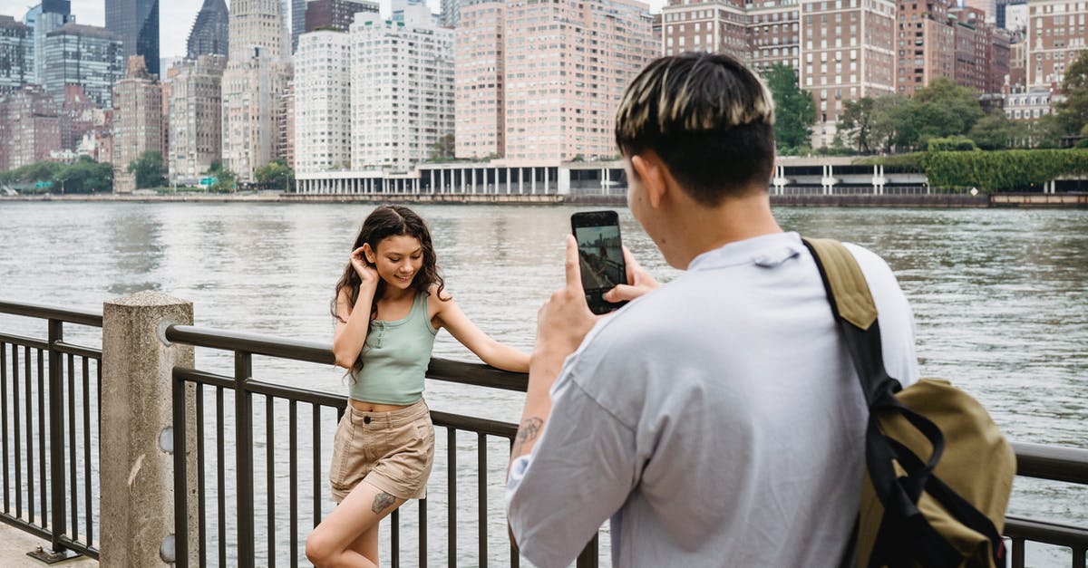 What factors affect a unit's contribution to city defense? - Young man photographing girlfriend on smartphone during date in city downtown near river What factors affect a unit's contribution to city defense? - Young man photographing girlfriend on smartphone during date in city downtown near river