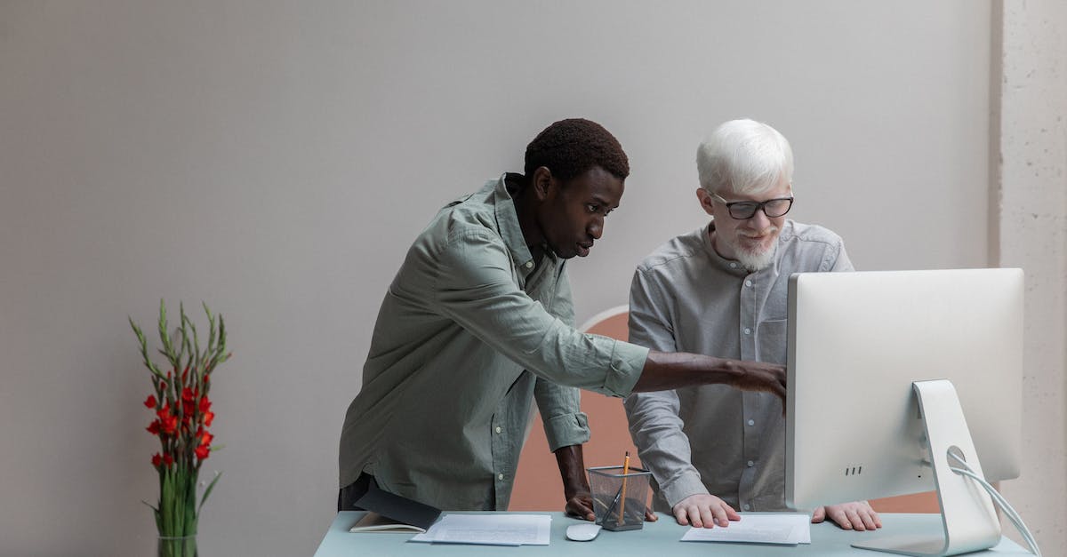 What features differ between the Xbox 360 and PC versions of Minecraft? - Concentrated African America man and albino male standing near table while browsing computer during work in modern office with flower What features differ between the Xbox 360 and PC versions of Minecraft? - Concentrated African America man and albino male standing near table while browsing computer during work in modern office with flower