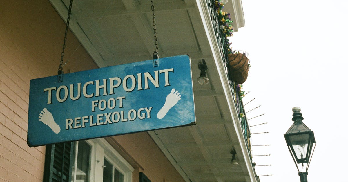 What FrontierNav locations cannot be reached on foot? - From below of signage with touchpoint foot reflexology text hanging on chains on ceiling of residential building near entrance