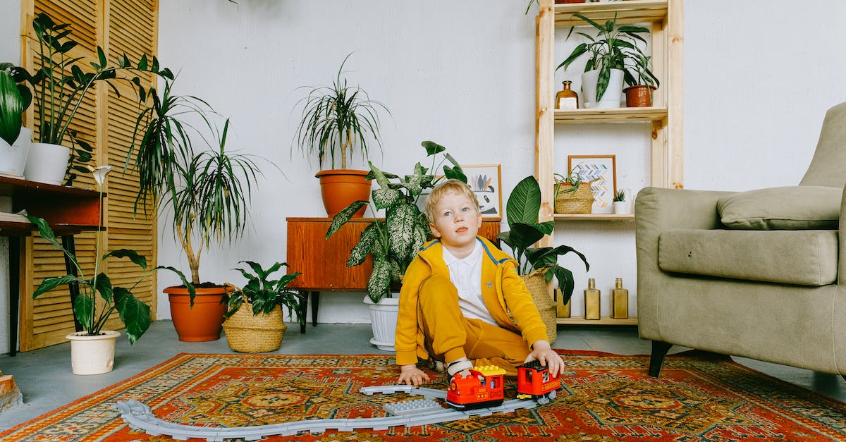 What game is this (looks like something related with House of Cards) - Playful child in casual wear sitting on carpet in cozy living room and playing with plastic railway and train while having fun during weekend What game is this (looks like something related with House of Cards) - Playful child in casual wear sitting on carpet in cozy living room and playing with plastic railway and train while having fun during weekend