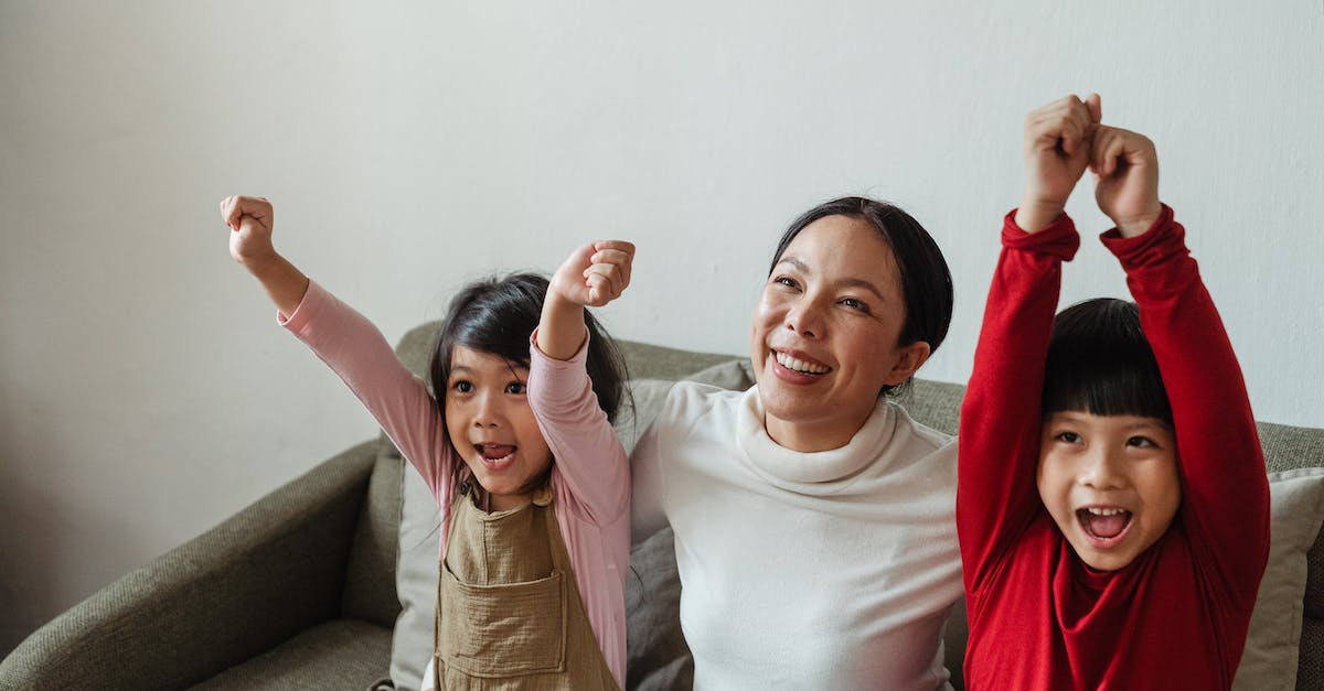 What games can the Vita TV (PlayStation TV) play? - Cheerful ethnic mother and children watching game on TV sitting on sofa and celebrating winning