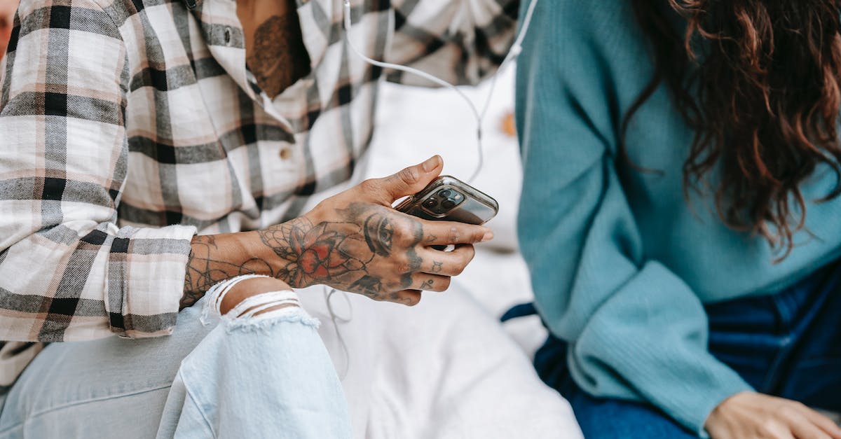 What genre is best for a song about shoes? - Crop unrecognizable diverse friends in casual clothes sitting and listening to music in earphones in daytime