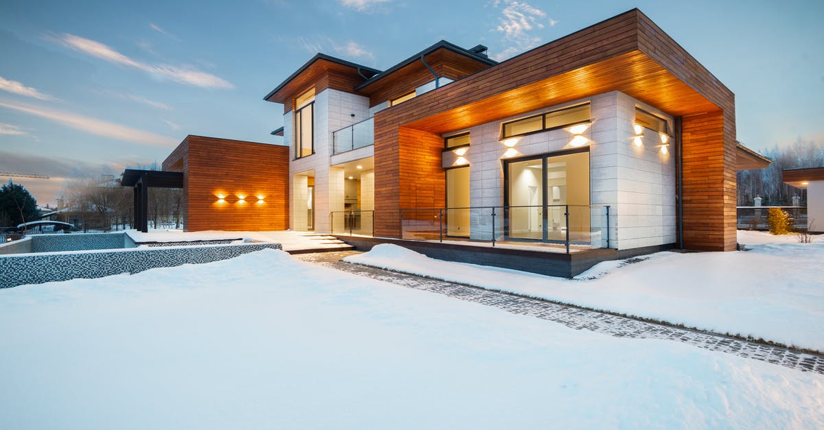 What happened to my villagers? - Exterior architecture of private suburban cottage house with stone and wooden facade and large windows overlooking spacious snow covered yard in winter day