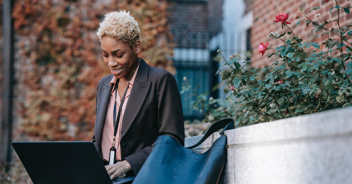 What happens if you delete your Nintendo Network ID, and where do the badges go? - Smiling young African American female freelancer in stylish jacket with badge working on laptop while sitting on bench near flowerbed