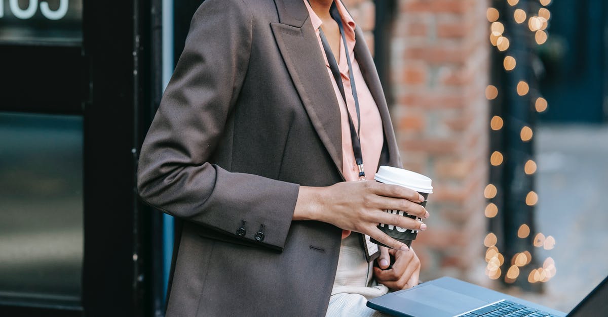 What happens if you delete your Nintendo Network ID, and where do the badges go? - Crop anonymous African American female entrepreneur in classy jacket with badge using laptop and drinking coffee to go