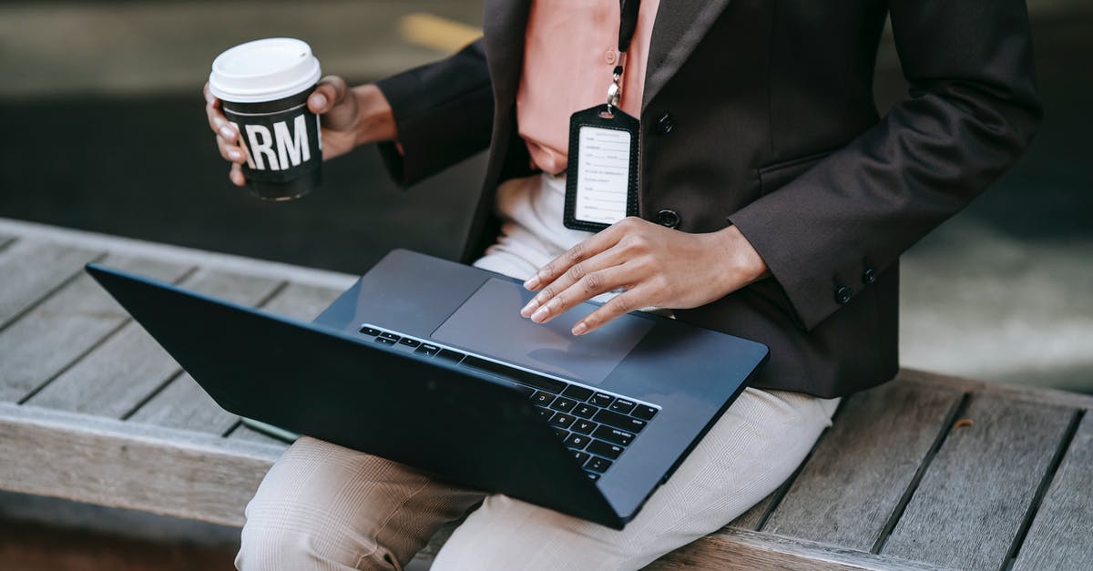 What happens if you delete your Nintendo Network ID, and where do the badges go? - From above of crop anonymous female entrepreneur in stylish black jacket with badge sitting on wooden bench drinking coffee and using laptop