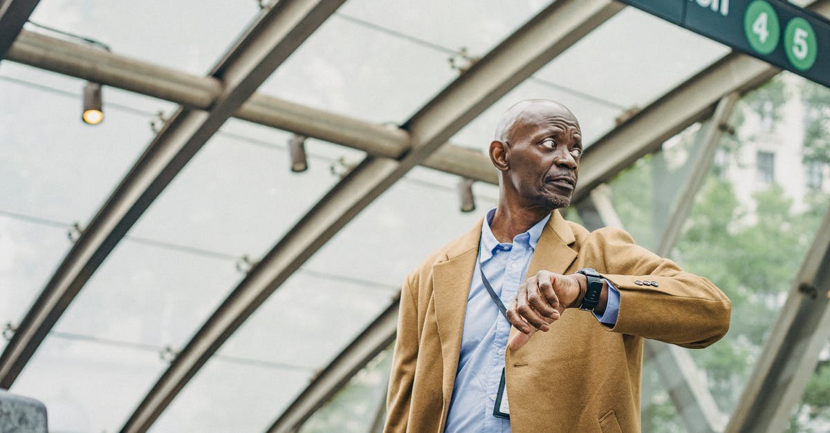 What happens if you wait 18 hours? - Serious African American businessman in formal clothes standing in subway station and checking time on wristwatch while looking away thoughtfully What happens if you wait 18 hours? - Serious African American businessman in formal clothes standing in subway station and checking time on wristwatch while looking away thoughtfully