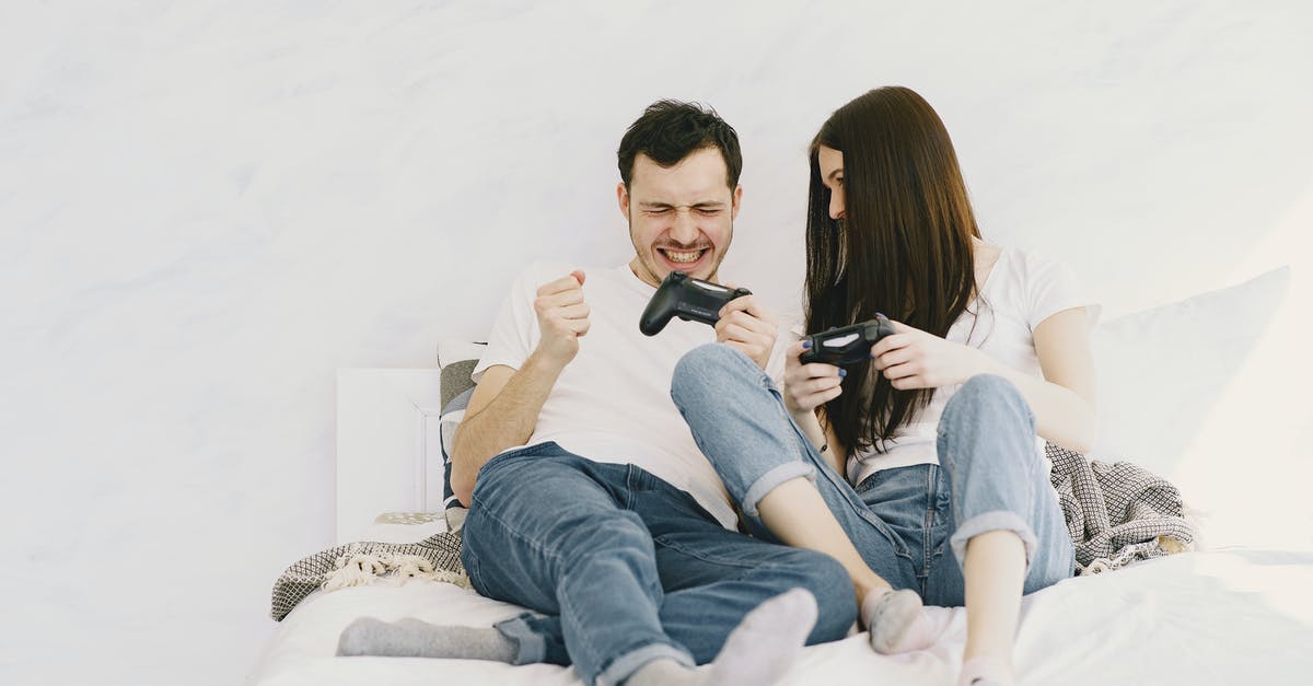 What happens to free games obtained through PlayStation Plus after it expires? - Happy man in white t shirt and jeans with closed eyes and game pad showing yes gesture after winning and lying on bed near girlfriend at home