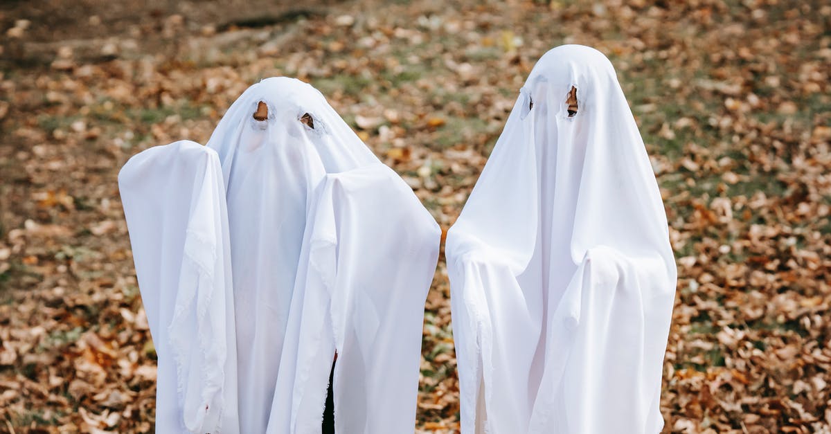 What happens to Trick-or-Treat Bags after the Halloween event? - Anonymous kids in scary ghost costumes standing on fallen leaves in autumn park