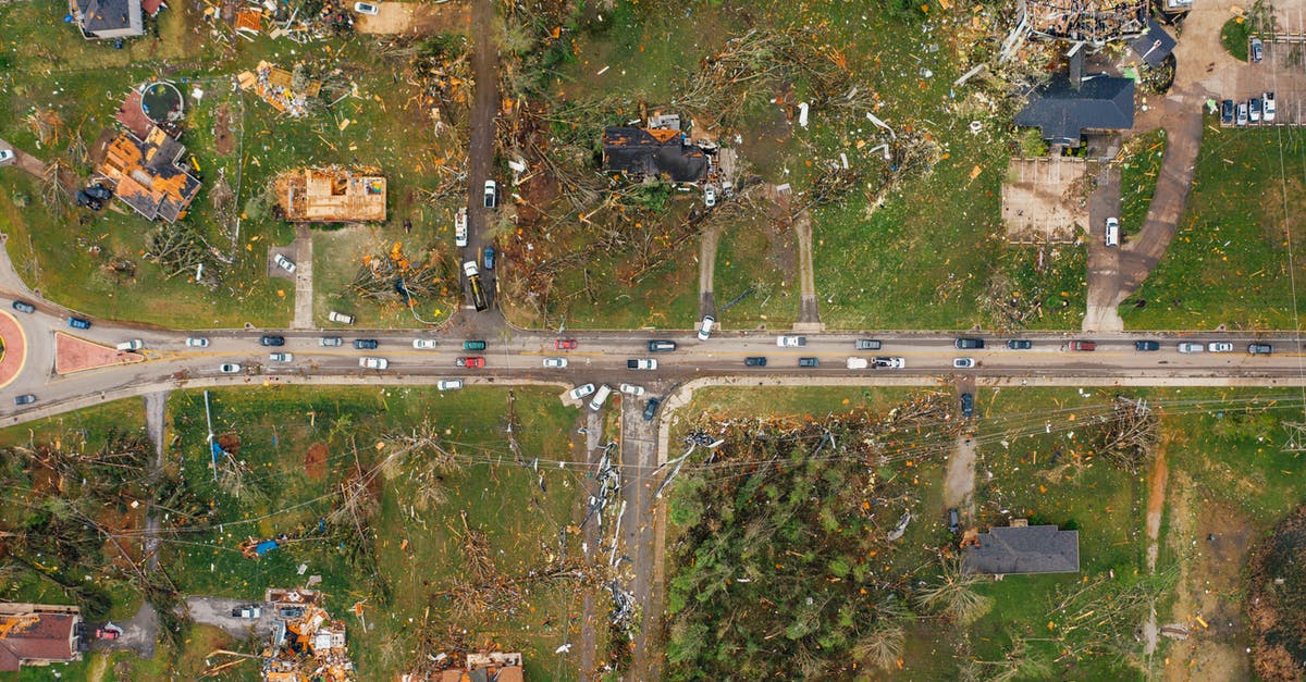 What impact is there to bulldozing housing? - Aerial view of village houses ruined by wild storm near windthrown trees and electricity lines