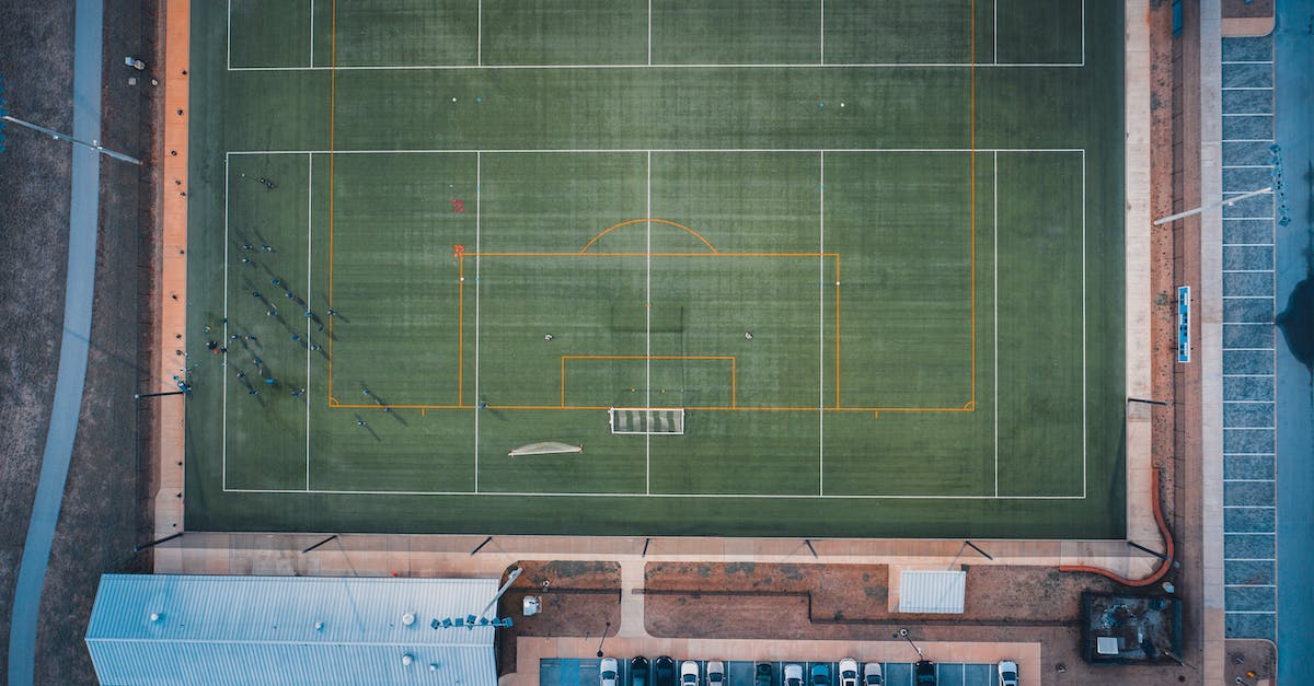 What is a 'clutch' in competitive gaming? (Not in the car sense) - Aerial view of distant unrecognizable people standing on green grassy rugby field on sunny day