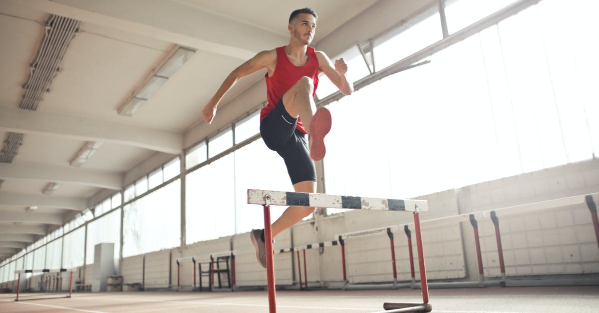 What is an any % speed run in Diablo 2? - Powerful male athlete jumping over hurdle on running track while training at sports hall