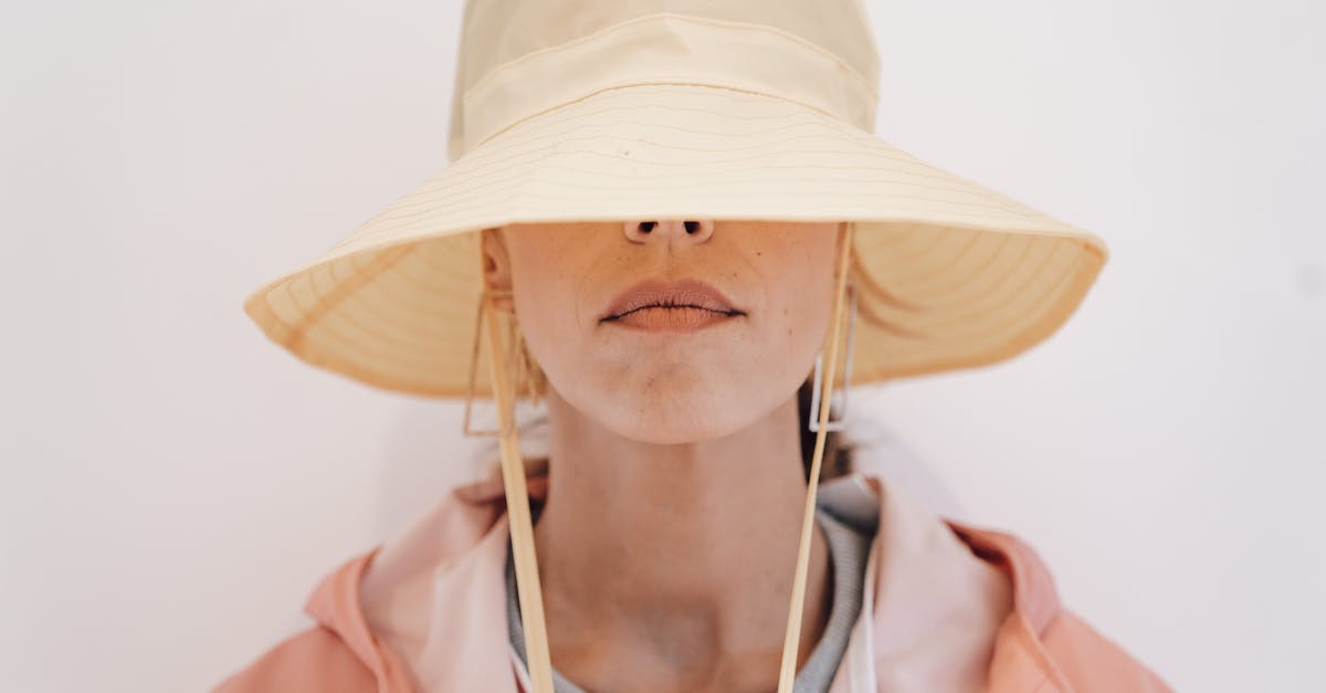 What is behind the mysterious door? - Serious female in outerwear and earrings hiding face with stylish hat against white background What is behind the mysterious door? - Serious female in outerwear and earrings hiding face with stylish hat against white background