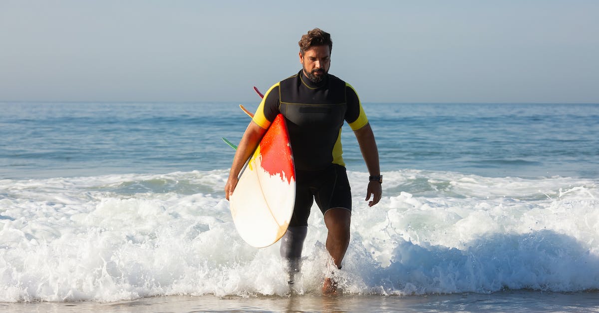 What is called "maximum carry weight" in the formula for strength advancement - Full body sporty ethnic male surfer with leg prosthesis carrying surfboard and walking in foamy seawater towards sandy shore on sunny day