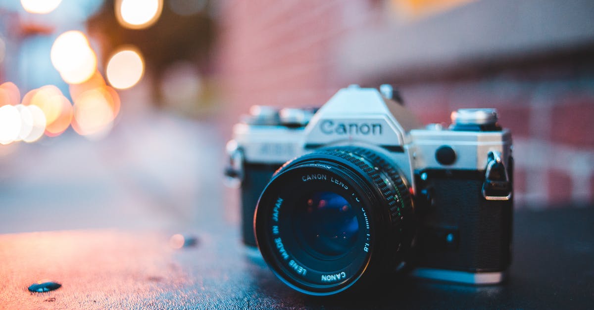 What is causing my light level to drop? - Ground level of vintage photo camera on sidewalk with water drops near urban building in twilight