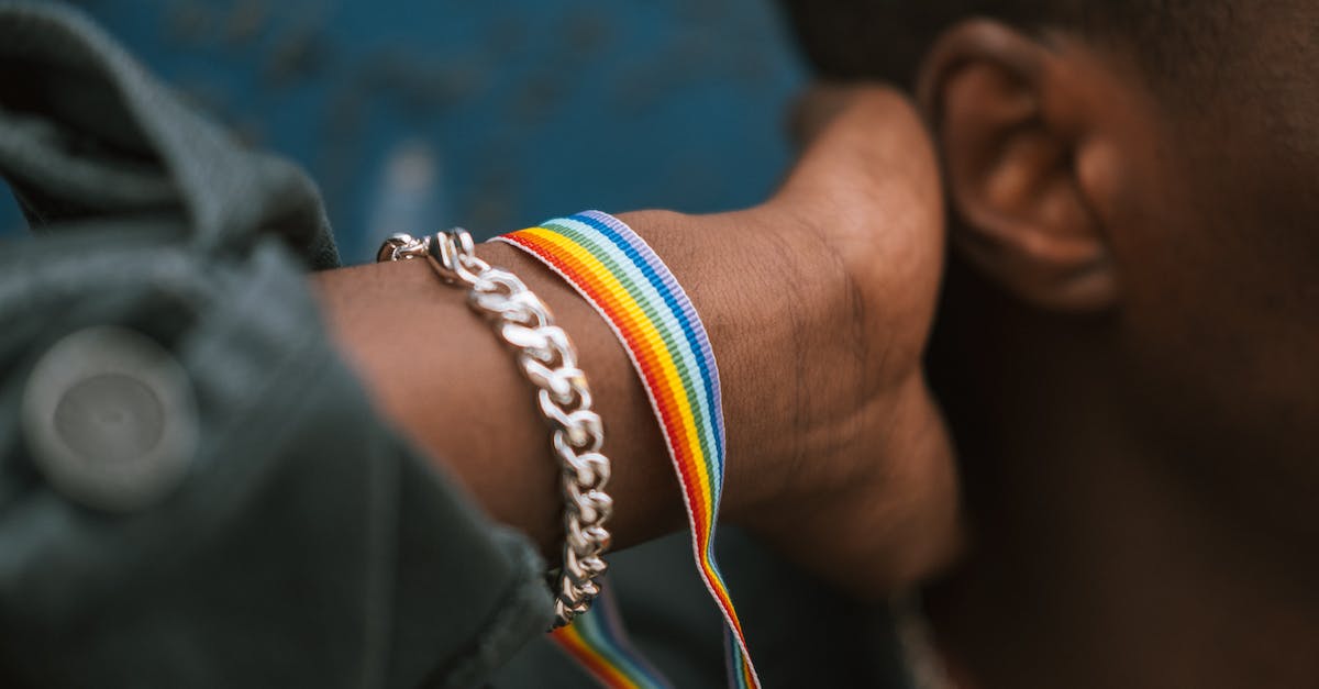 What is the benefit of Accept Culture change? - Crop faceless black man wearing pride bracelet and touching neck What is the benefit of Accept Culture change? - Crop faceless black man wearing pride bracelet and touching neck