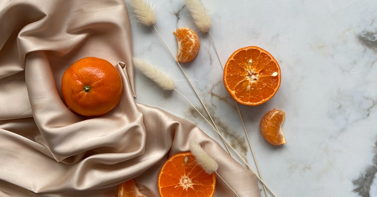 What is the benefit of ores obtained from silk touch? - Top view of fresh ripe slices of tangerine and oranges placed on crumpled fabric on marble surface with dried branches