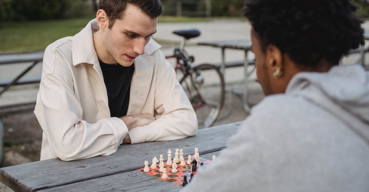 What is the best strategy to change my Princess' mood? - Concentrated young guy in casual clothes thinking while playing chess game with anonymous African American male friend in park What is the best strategy to change my Princess' mood? - Concentrated young guy in casual clothes thinking while playing chess game with anonymous African American male friend in park