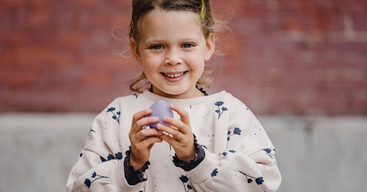 What is the blue/grey balloon on Happy Street? - Candid child in casual clothes looking at camera with small balloon in town in daylight What is the blue/grey balloon on Happy Street? - Candid child in casual clothes looking at camera with small balloon in town in daylight