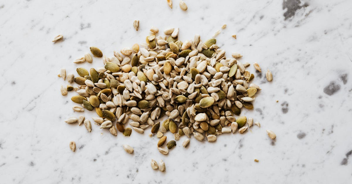 What is the chance to find a pokemon at a spot with green leaves? - From above of oval shaped dried pumpkin seeds with green and gray shell spilled on marble surface with spots