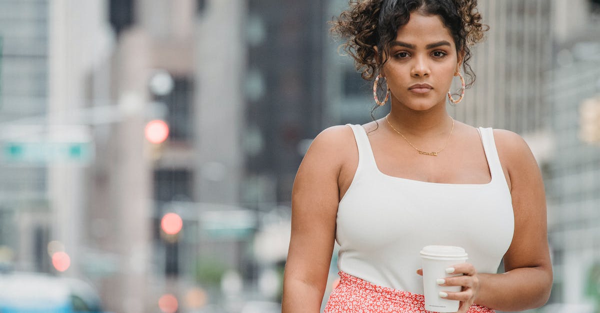What is the city on top of Sin? - Serious ethnic female standing with cup of takeaway coffee on street What is the city on top of Sin? - Serious ethnic female standing with cup of takeaway coffee on street