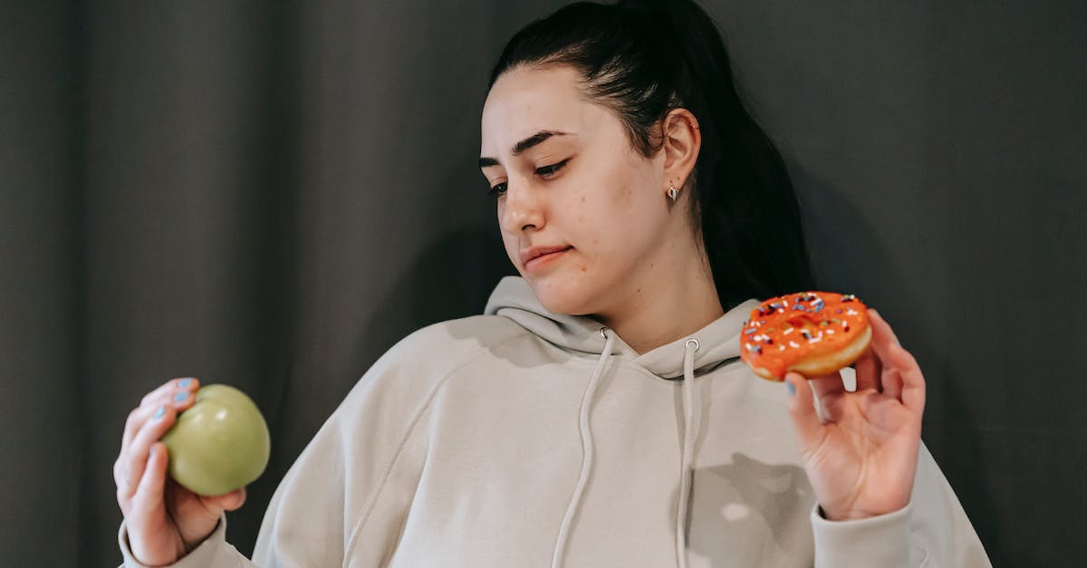 What is the criteria for the other donut option to become viable in Don't get fired? - Pensive female wearing casual hoodie deciding between healthy green apple and sweet doughnut in studio