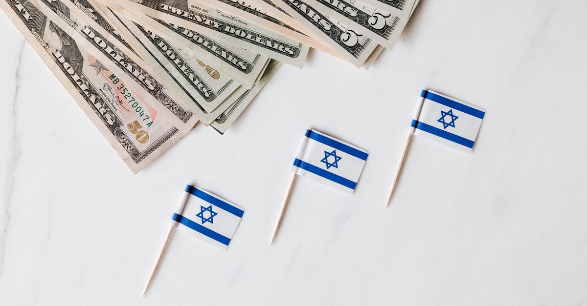 what is the difference between a flag and a teleporter? - Top view of bundle of different nominal pars dollars and Israeli flags on toothpicks placed on white surface of marble table